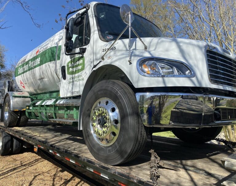 A propane truck transported on a flatbed trailer.