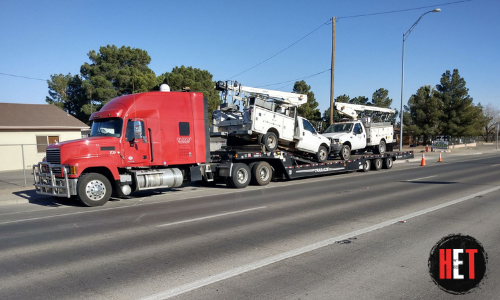 two ford work trucks shipped on a trailer