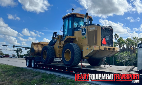 John Deere wheel loader transported on a trailer.